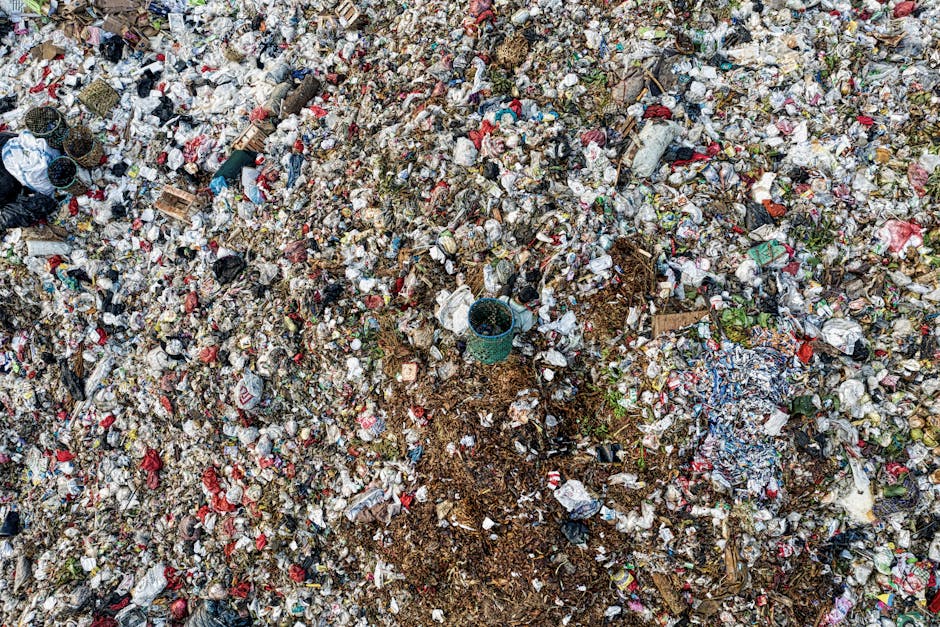 An aerial view of a cluttered area of makeshift structures and sheds constructed from corrugated metal sheets, with varying shades of silver and grey, some showing signs of rust and wear. The scene in